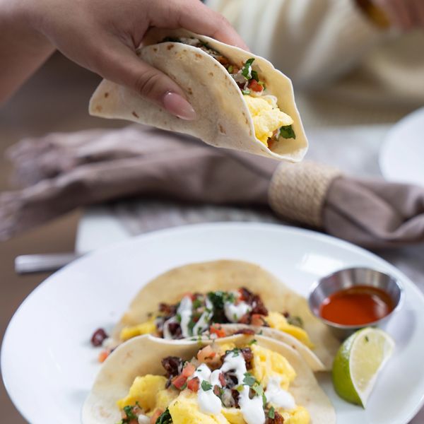 Hand holding a breakfast taco with scrambled eggs and salsa.