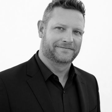 Black and white portrait of a smiling middle-aged man in a suit.