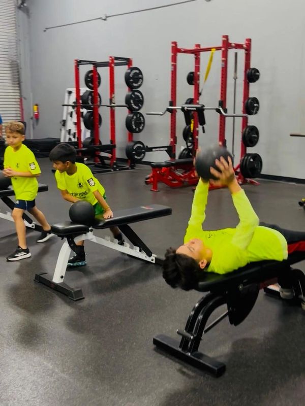 Kids exercising with medicine balls in a gym setting.