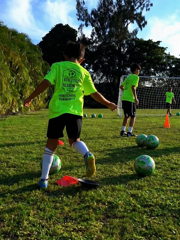 Children practicing soccer drills on a sunny field with bright green shirts.