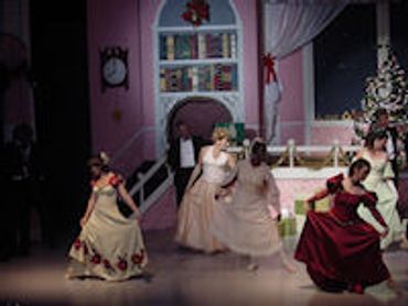 Women dancing in elegant dresses on stage.