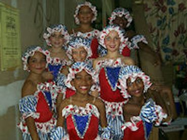 Group of girls in colorful costumes smiling.
