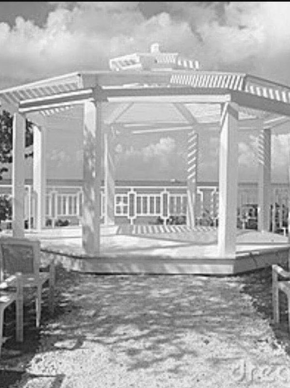 White gazebo with chairs set for an outdoor event by the ocean.