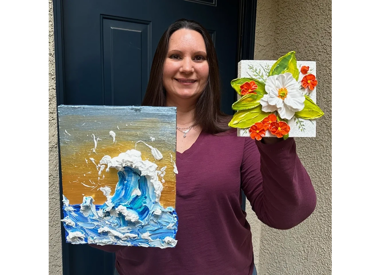 Tina Bailey is holding two of her acrylic creations. 