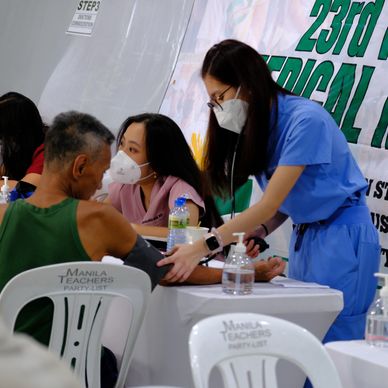 Healthcare workers check a man's blood pressure in a medical setting.