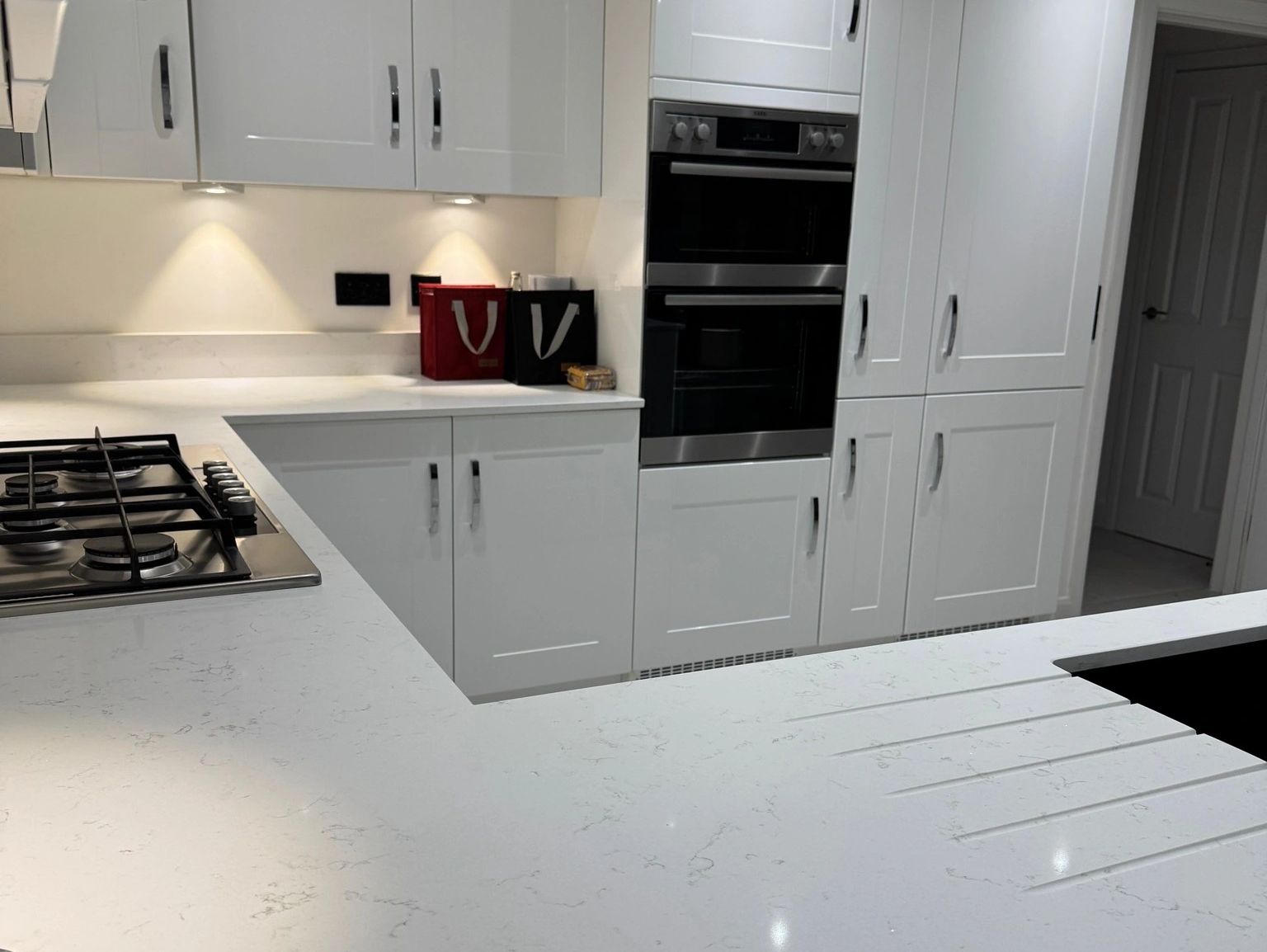 Modern white kitchen with sleek countertops and built-in appliances.