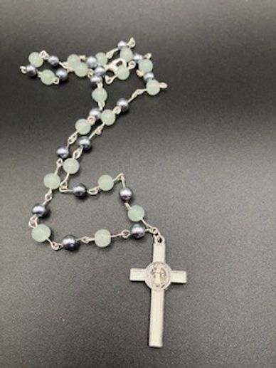 Rosary beads with a silver cross on a black background.