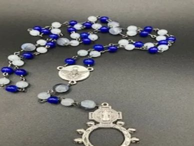 Blue and white beaded rosary with silver crucifix on gray surface.