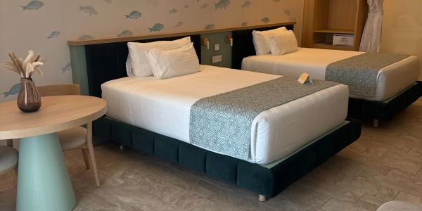 Modern hotel room with two beds and a round table.