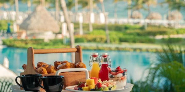 A refreshing breakfast setup by the pool with croissants, fruits, and drinks.