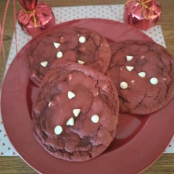 Red velvet cookies with white chocolate chips on a red plate.