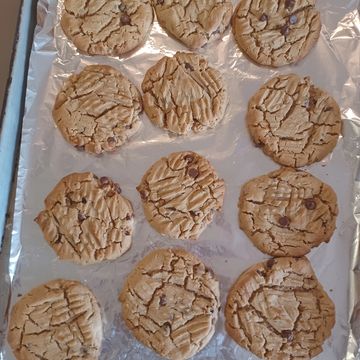 Freshly baked chocolate chip cookies on a foil-lined tray.