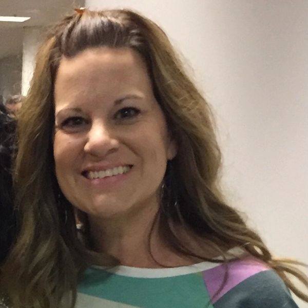 Smiling woman with long hair wearing a colorful striped shirt.