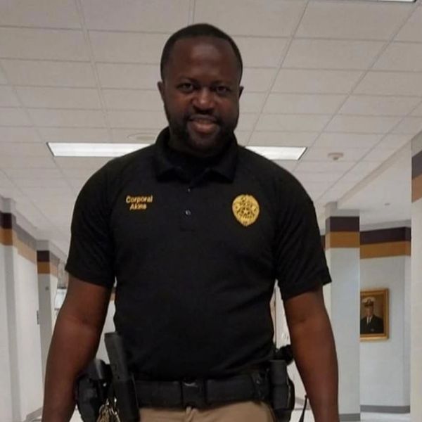 A police officer standing with a German Shepherd police dog in a hallway.