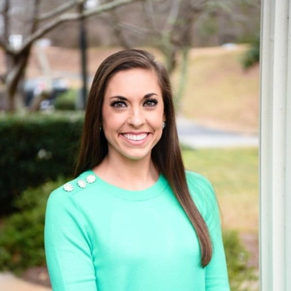 Smiling woman in a mint green sweater outdoors.