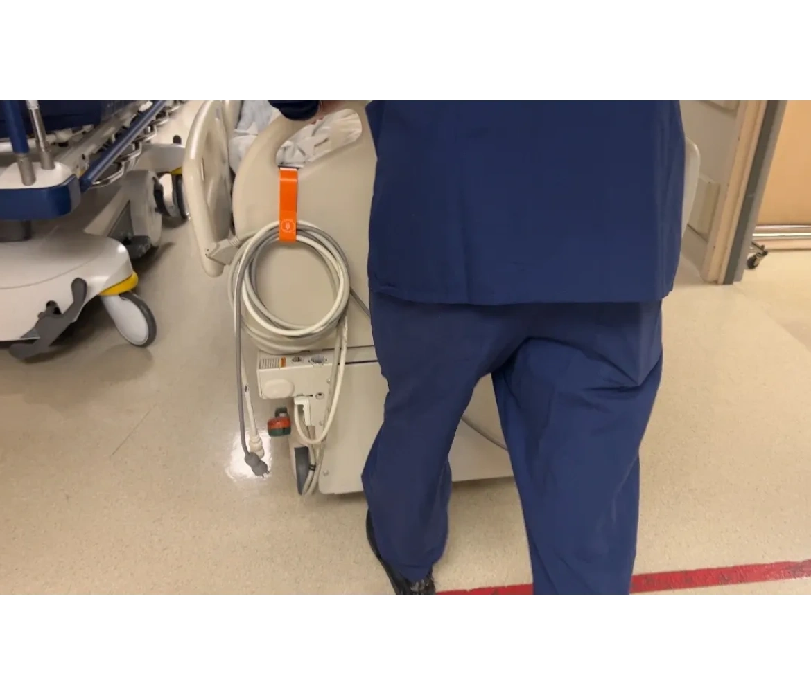 healthcare worker pushing in-patient bed with cordclear's hospital cord holder