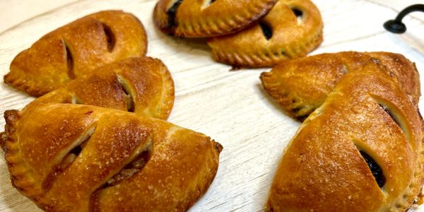 Golden-brown baked pastries with slits on top arranged on a wooden surface.