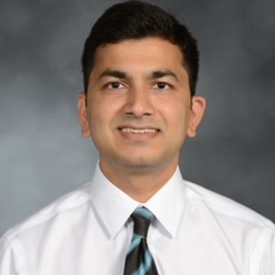 Professional headshot of a young man in a white shirt and tie.