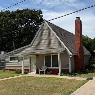 A small house with a sloped roof and red brick chimney.