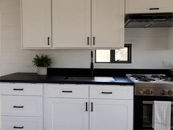 Minimalist kitchen with white cabinets and black countertop.