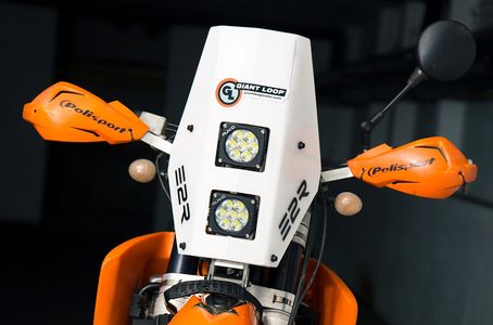 Moto naranja con protección en los espejos y faros delanteros cuadrados.