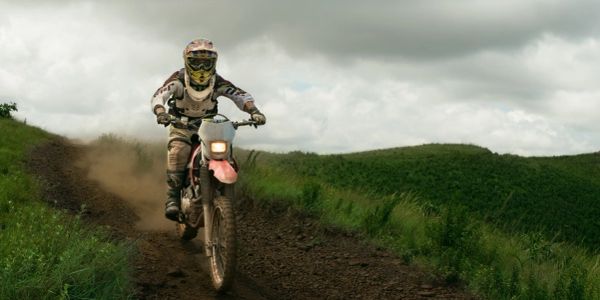 Persona en moto de montaña en camino de tierra.