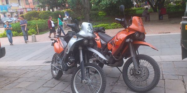 Two parked motorcycles on a sidewalk in an urban area.