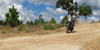 Persona conduciendo una moto en un camino de tierra.