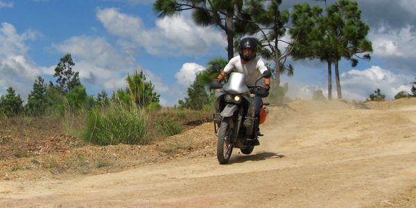 Person riding a motorcycle on a dirt road.
