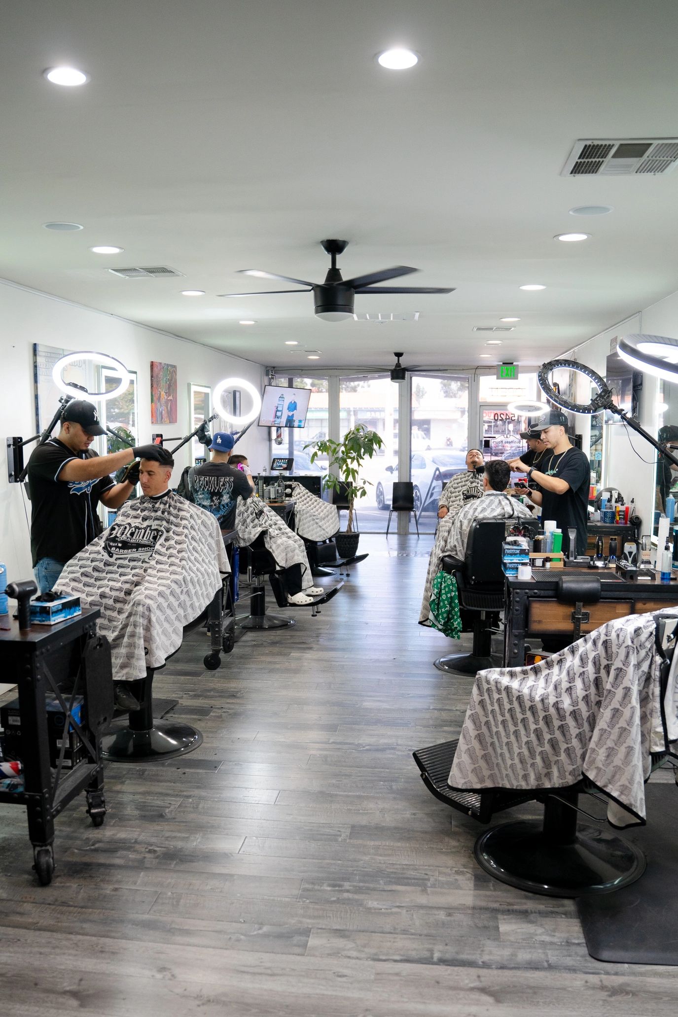 Modern Barbershop interior with crew of barbers cutting clients hair in Professional workstations.