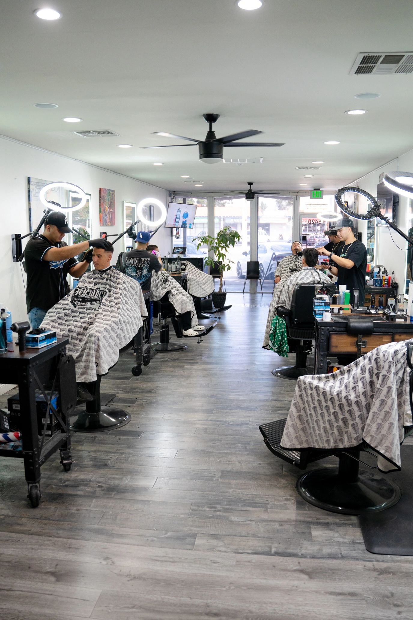 Modern Barbershop interior with crew of barbers cutting clients hair in Professional workstations.