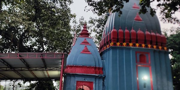Blue and red temple surrounded by trees and a sheltered area.