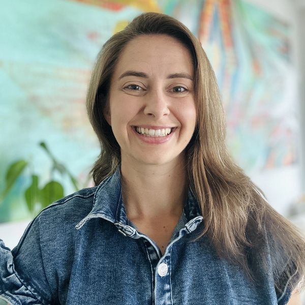 Smiling woman in denim jacket indoors.