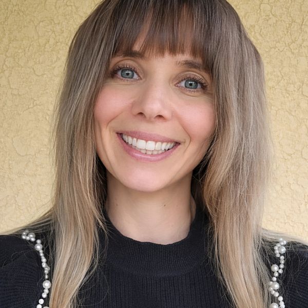 Smiling woman with light brown hair and bangs.