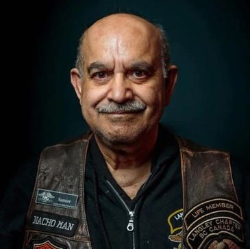 Portrait of a smiling man wearing a leather vest with patches.