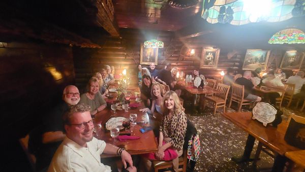 Group of friends dining together in a cozy, warmly lit restaurant with rustic decor.