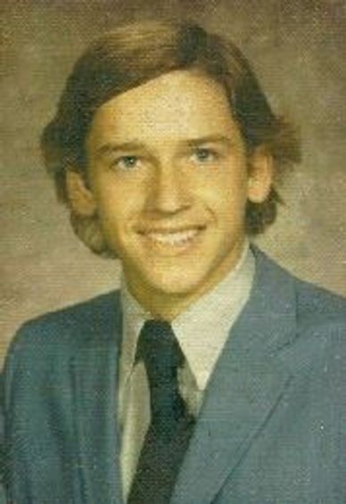 Young man in a blue suit and tie smiling for a formal portrait.