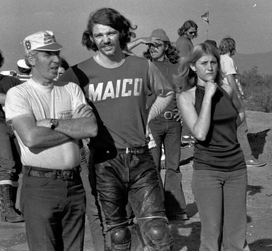 Three people standing together outdoors, dressed casually in vintage style.