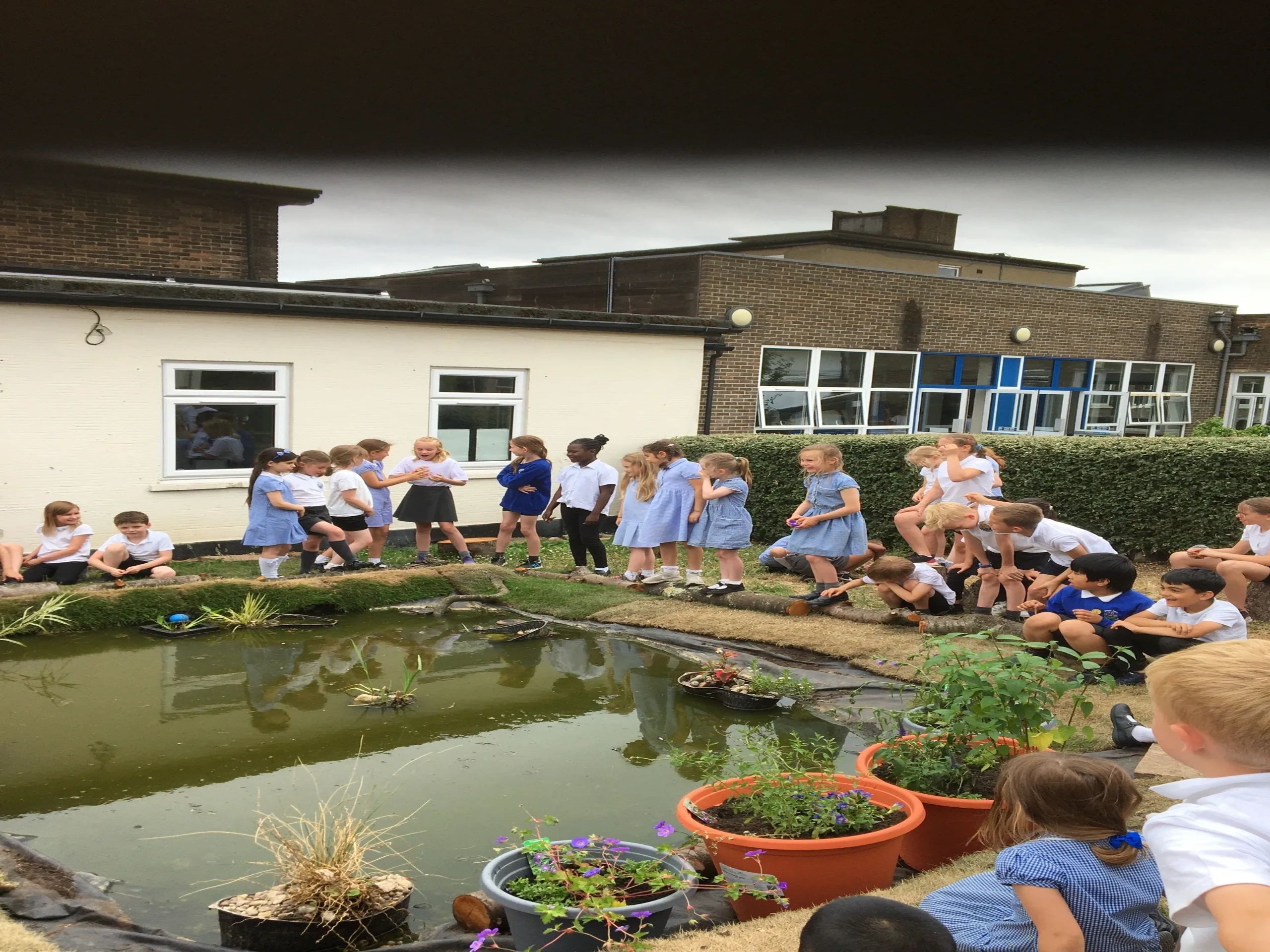 Children sitting proud of their achievement in building the school pond Summer 2023