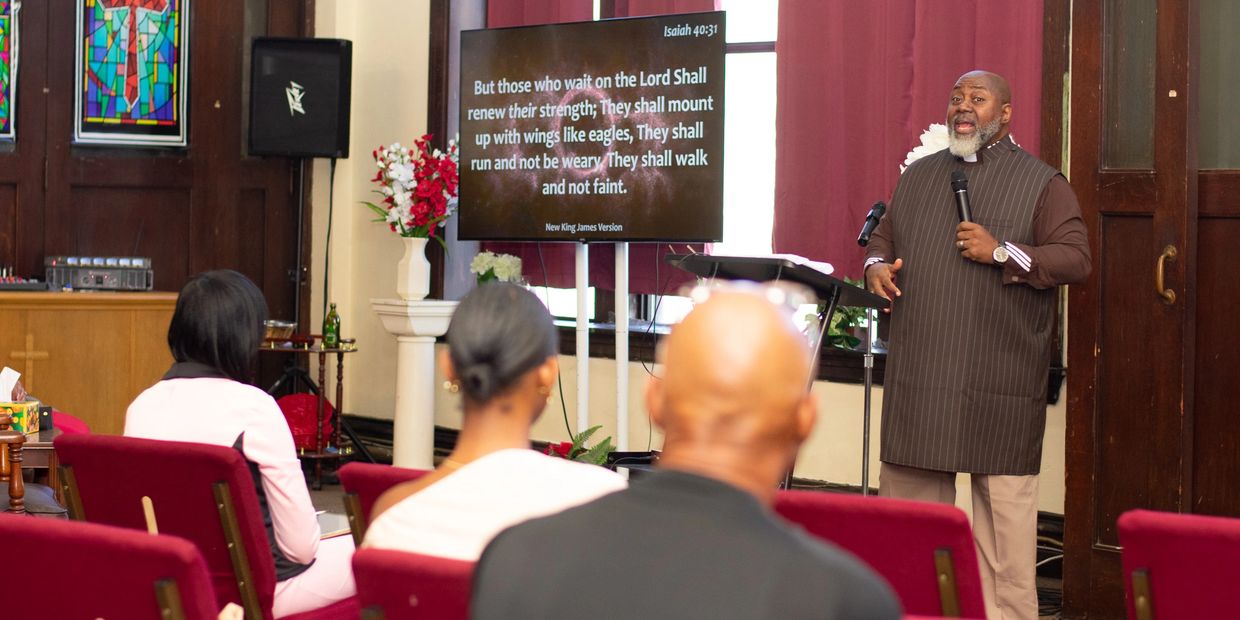 A pastor preaching to a small congregation in a church setting.