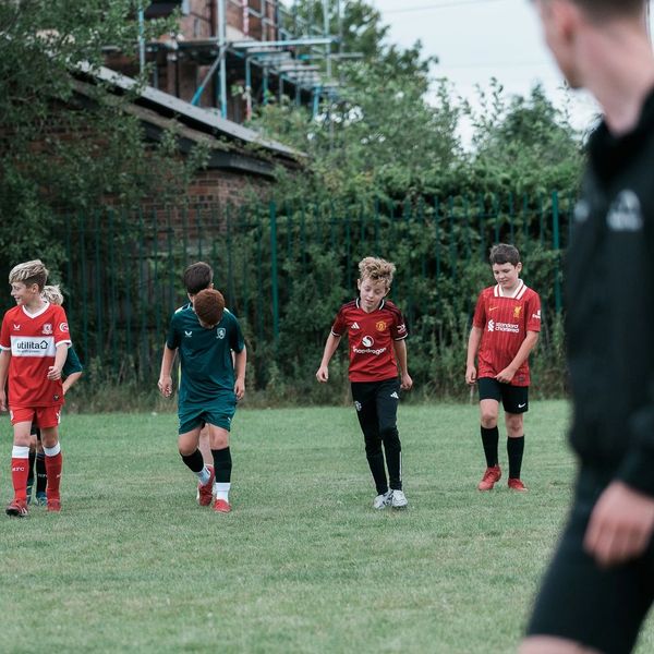 A group of young boys in soccer uniforms walking on a grassy field.