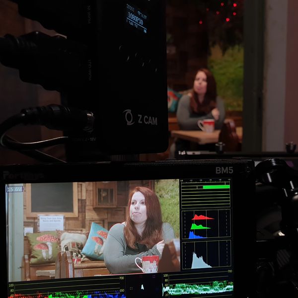 A behind the scenes shot of a video production, showing a camera monitor and a subject framed