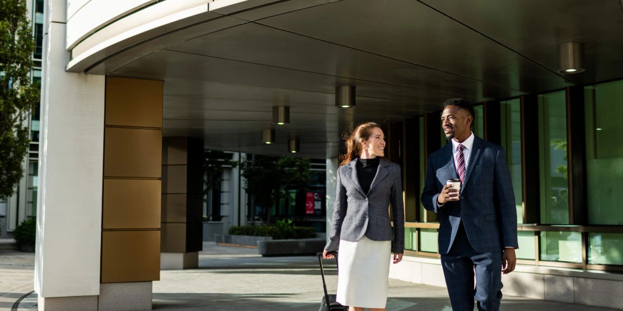 Two business professionals walking and talking outside an office building.