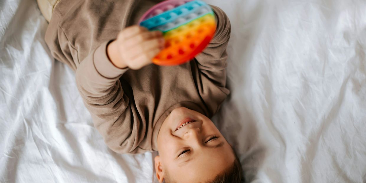 Child playing with a rainbow pop-it toy.