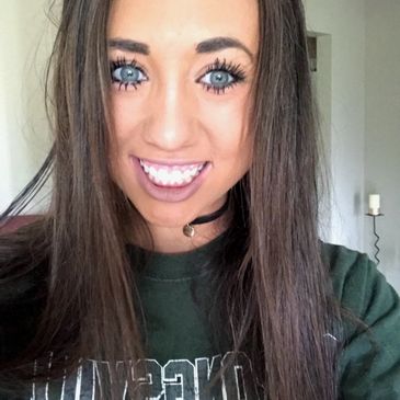 Young woman smiling with long hair and blue eyes.