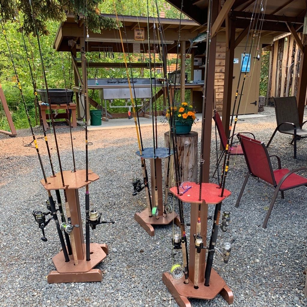 Fishing rods organized on wooden stands at an outdoor fishing area.