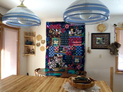 Cozy dining area with a colorful quilt wall hanging and rustic decor.