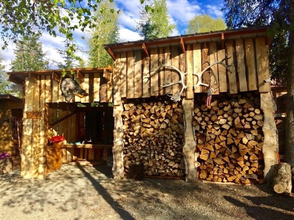 Wood storage sheds with antlers and a bear decoration in a sunny outdoor setting.