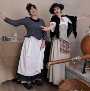 Two women in Victorian costume singing in the Isle of Cumbrae Gin Distillery.