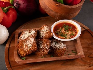 Breaded fried mushrooms with marinara sauce on a wooden platter.
